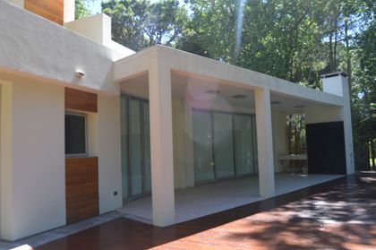 Fachada moderna con patio cubierto y detalles en madera — proyecto CARILO - Boyero, por LADAGA-RUARTE-Pinamar, en Cariló