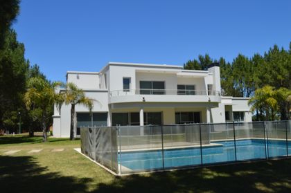 casa moderna blanca con piscina y jardín frondoso — proyecto LA HERRADURA - Boulevard I, por LADAGA-RUARTE-Pinamar, en Pinamar
