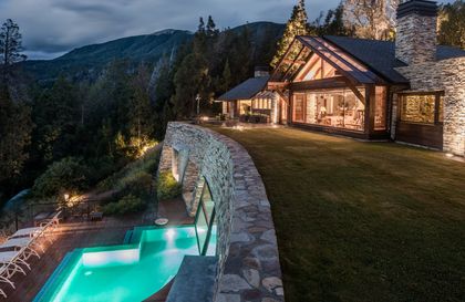 casa lujosa con piscina iluminada y montañas de fondo — proyecto Casa Villa La Angostura 2, por Sidoni & Asociados, en Villa La Angostura