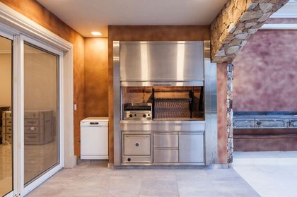 Quincho moderno con detalles en acero inoxidable y piedra — proyecto CK House, por A+R Arquitectos