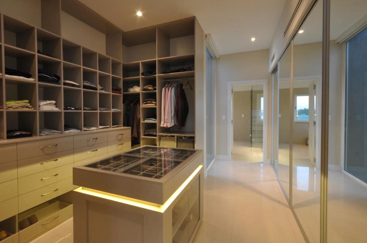 Amplo closet moderno com ilha central e prateleiras integradas — projeto OP House, por A+R Arquitectos