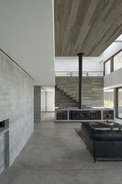 Living moderno de hormigón con doble altura y chimenea — proyecto Casa 10, por Luciano Kruk