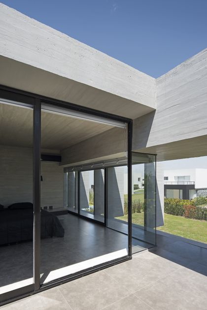 Terraza minimalista con ventanal y vista al jardín, arquitectura contemporánea — proyecto Casa BLQ, por Luciano Kruk