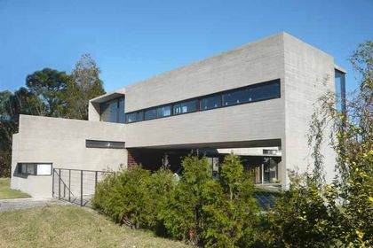 Casa moderna de hormigon visto con grandes ventanales y jardin arbolado — proyecto Casa Canning, por Luciano Kruk, en Canning