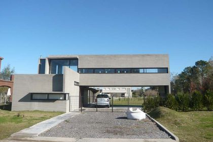 Casa moderna de hormigón con líneas geométricas y amplios ventanales — proyecto Casa Canning, por Luciano Kruk, en Canning