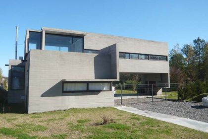 Casa contemporánea gris con amplios ventanales y fachada de hormigón — proyecto Casa Canning, por Luciano Kruk, en Canning