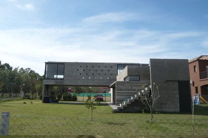Casa contemporánea gris con fachada de hormigón y jardín amplío — proyecto Casa Canning, por Luciano Kruk, en Canning