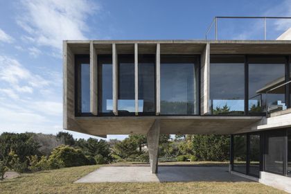 Casa moderna con fachada de hormigón y grandes ventanales, terraza deck — proyecto Casa Cariló, por Luciano Kruk, en Cariló