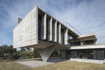 Casa contemporánea con fachada de hormigón y grandes ventanales — proyecto Casa Cariló, por Luciano Kruk, en Cariló
