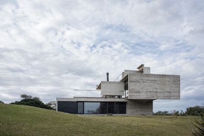 Casa contemporánea de hormigón con voladizo sobre césped verde — proyecto Casa Cariló, por Luciano Kruk, en Cariló