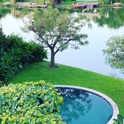 Pileta circular rodeada de césped y vegetación exuberante — proyecto CASA LAGUNA, por Estudio Xime Fontan Balestra, en Tigre