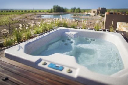 Jacuzzi blanco con vista a laguna y casa de campo al fondo — proyecto Rosell Boher Lodge , por Estudio Du 