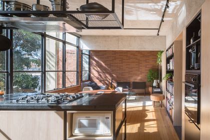 Cocina moderna con isla, ladrillo visto y gran ventanal con luz natural — proyecto Apartamento SQN 410, por Coda Arquitetos