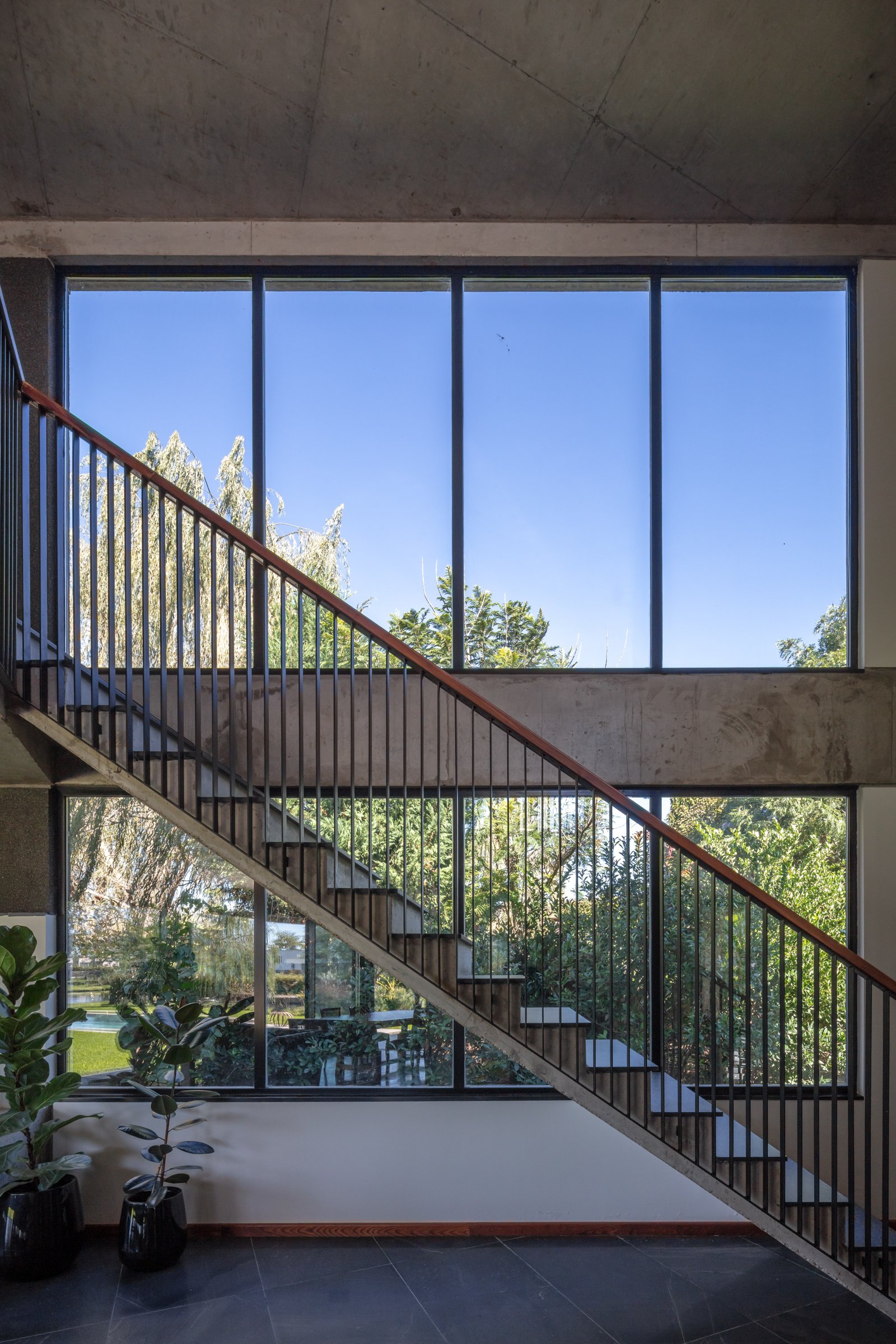 Escalera flotante moderna con ventanales altos y hormigón expuesto — proyecto La Martona UF280, por BARBALACO ARQUITECTOS, en Provincia de Buenos Aires