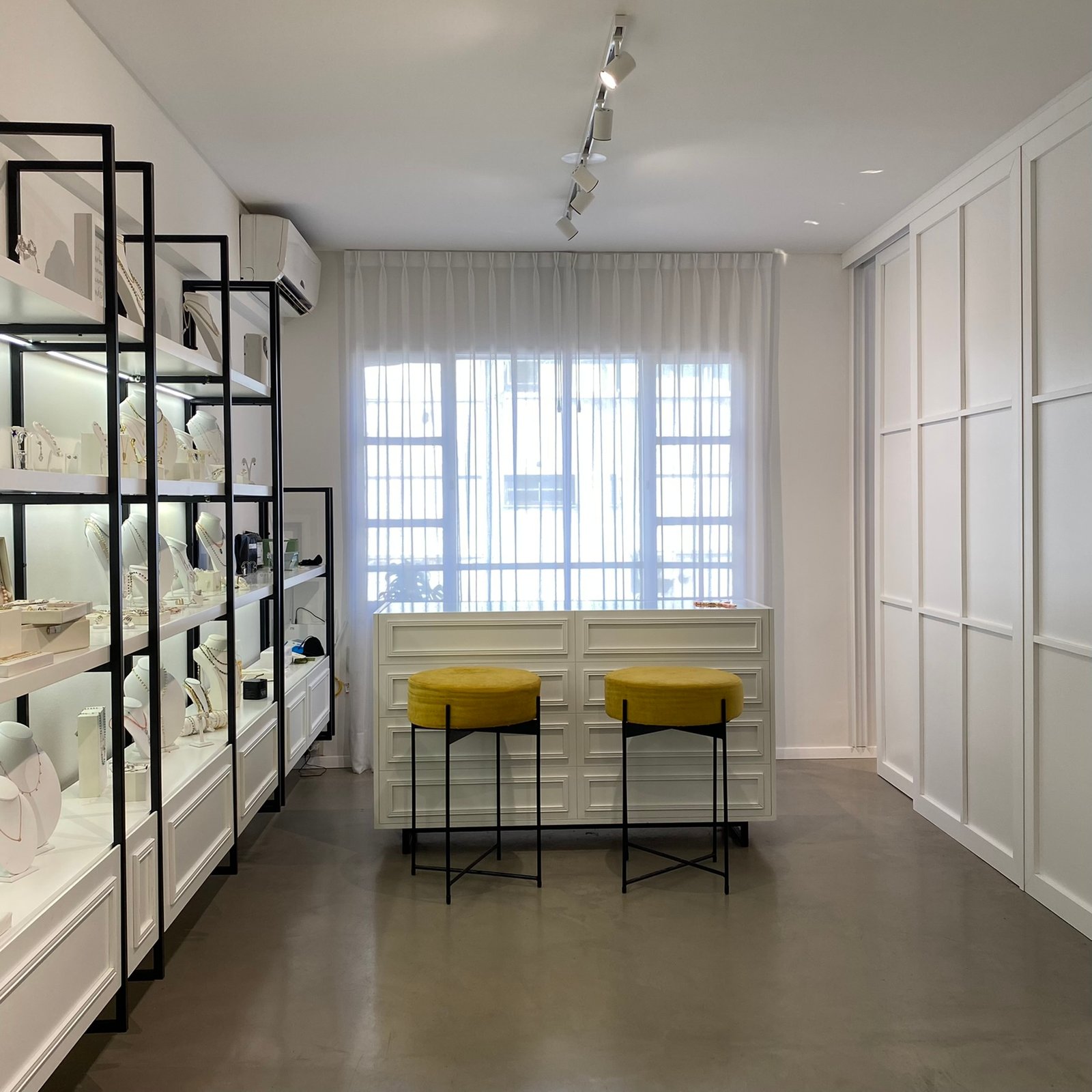 Loja de joias minimalista com assentos amarelos e prateleiras pretas — projeto Factory, por MDBK Arquitectura, em Palermo