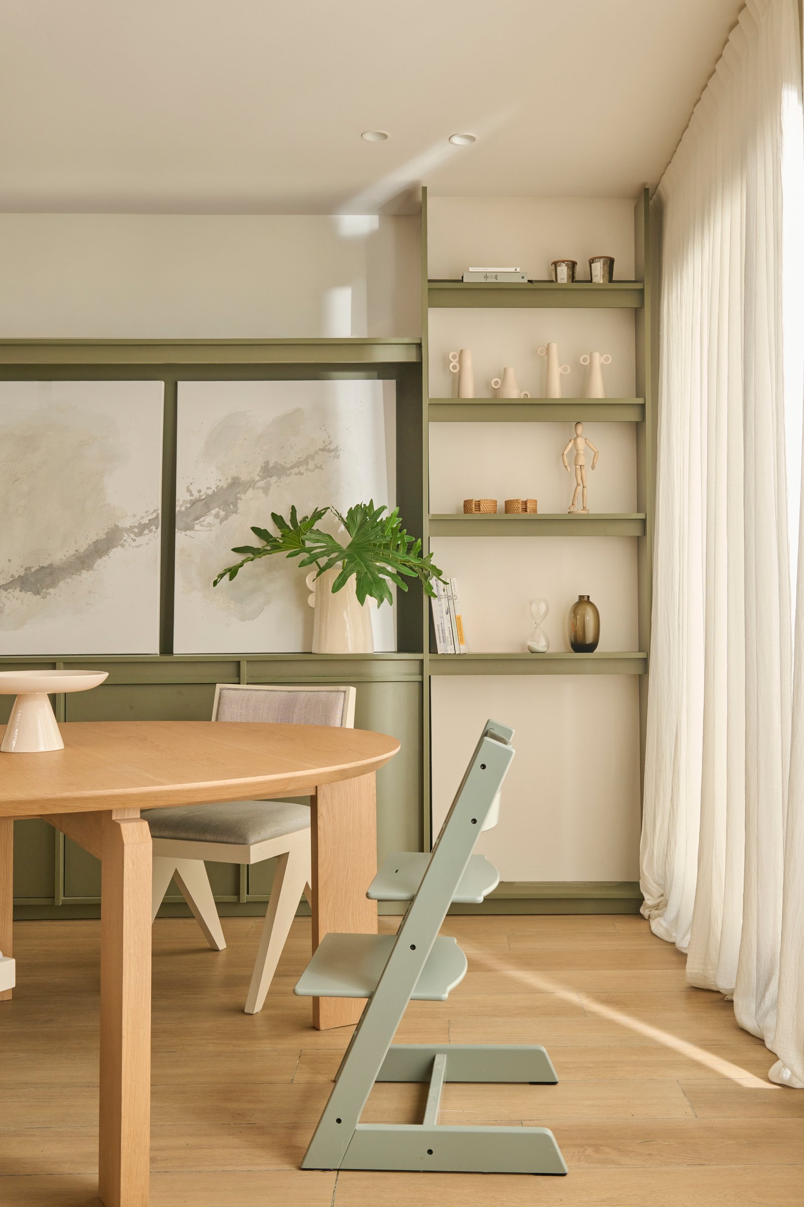 Comedor moderno escandinavo con mesa redonda de madera y estanterías verdes — proyecto VIRREY AVILES, por loom, en Buenos Aires