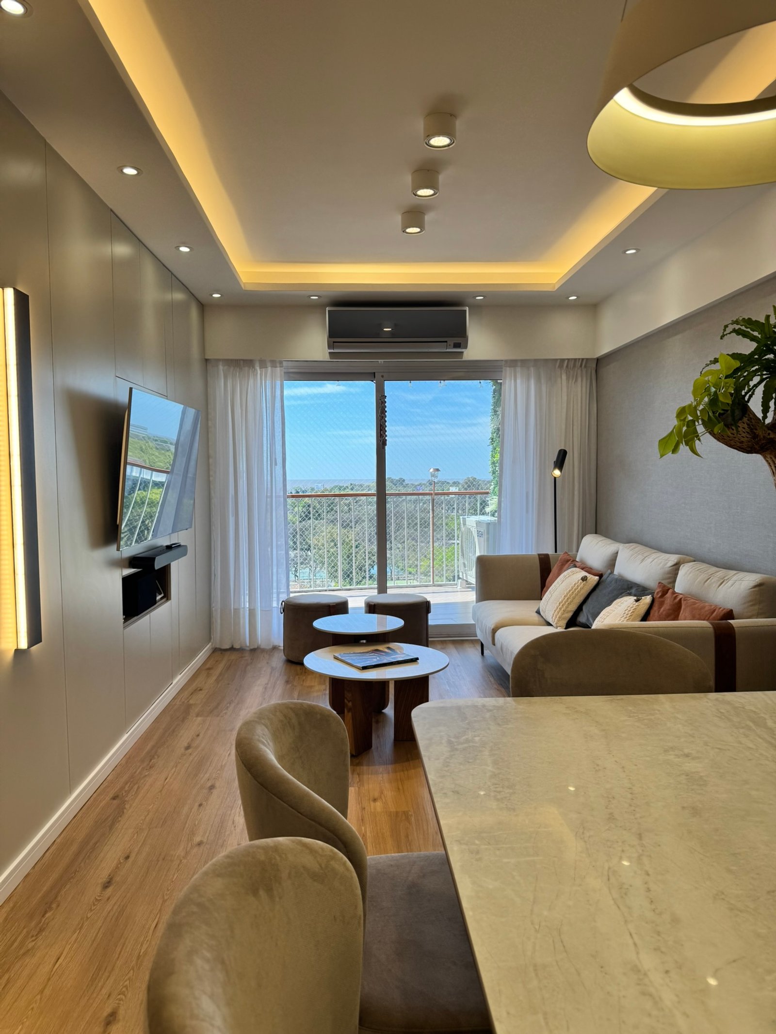 Living moderno con sofá curvo y luz indirecta — proyecto Libertador II, por MDBK Arquitectura, en Núñez