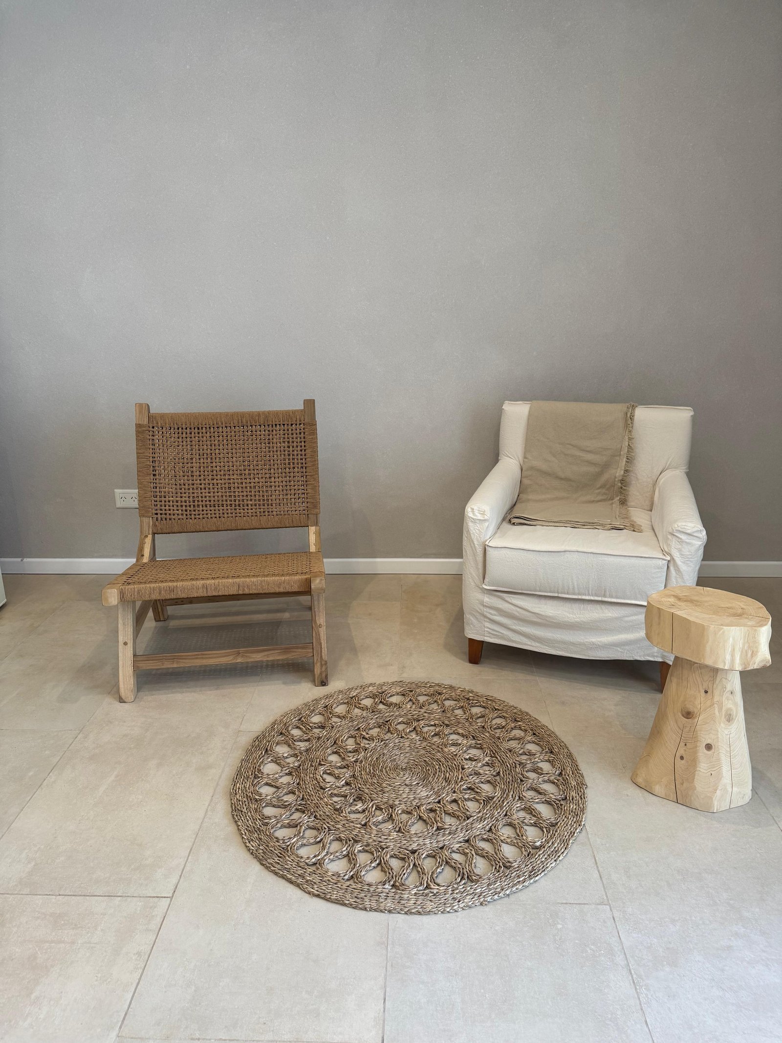 Living con sillón blanco, silla de junco y mesa de tronco — proyecto PROYECTO CASA BORA HOTEL, por ILVA, en Provincia de Buenos Aires