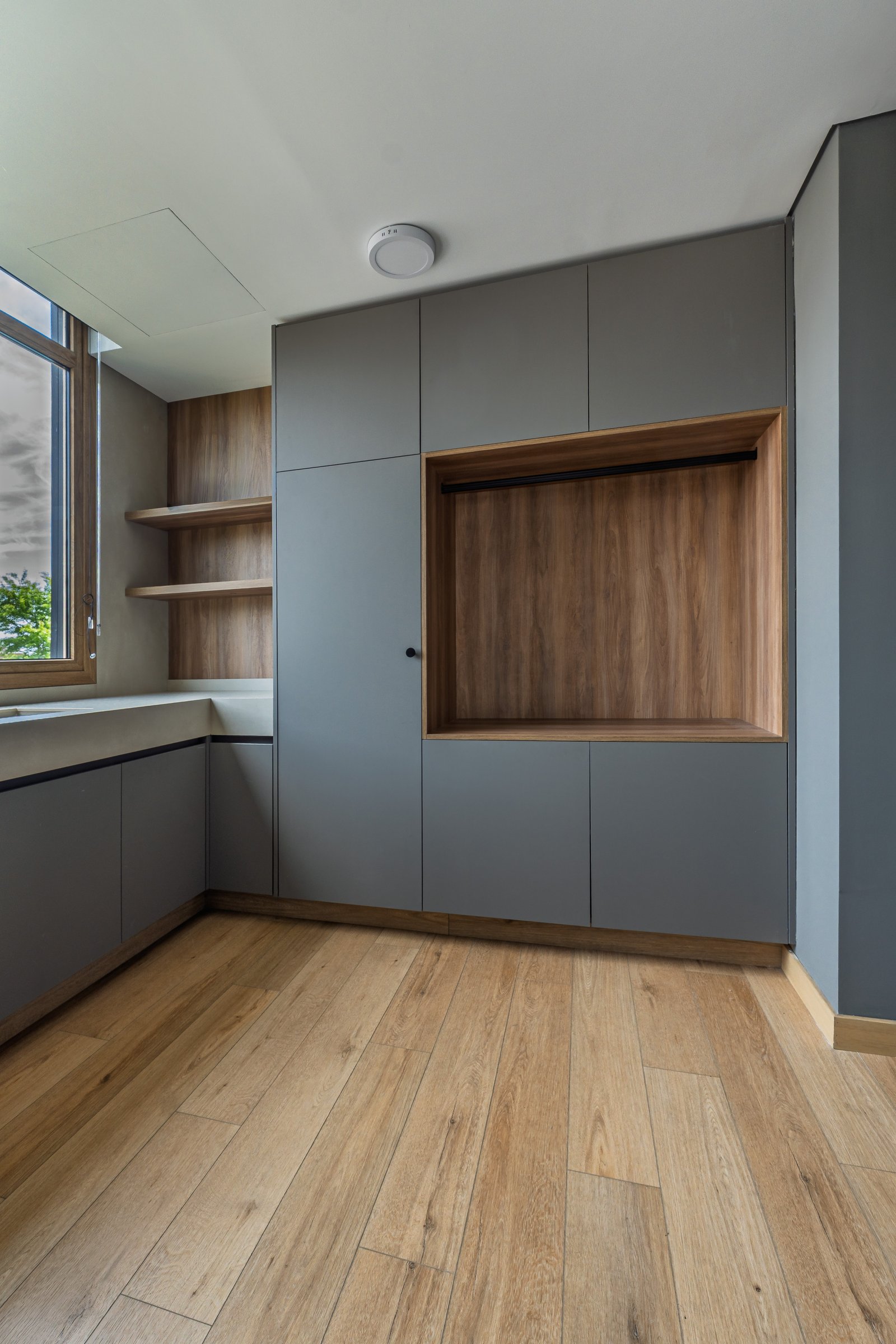 Interior moderno con armarios grises y nicho de madera — proyecto Castores - Estudio Gambotto, por ABEJA CONCEPT, en Los Castores