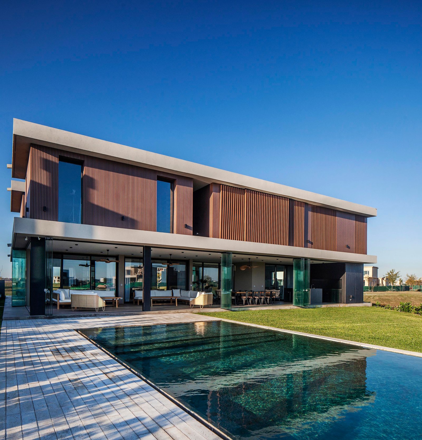 Casa moderna de madera y vidrio con piscina y deck exterior — proyecto CASA C313, por A'PRIMA - Arquitectura Sustentable, en Provincia de Buenos Aires