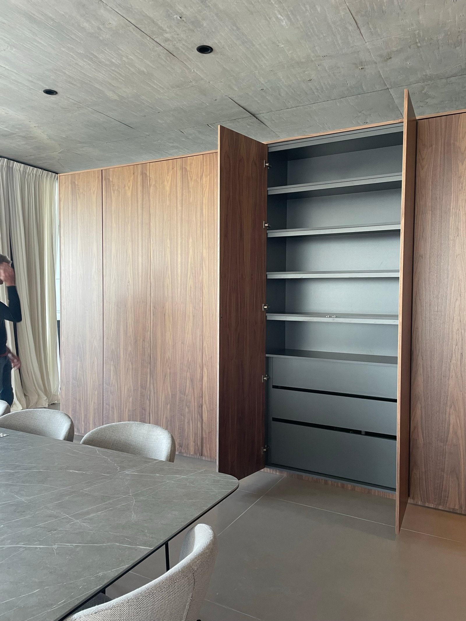 Comedor moderno con mesa de piedra, sillas, y gran armario de madera — proyecto Albanueva - Estudio Amado Cattaneo, por ABEJA CONCEPT, en Nordelta