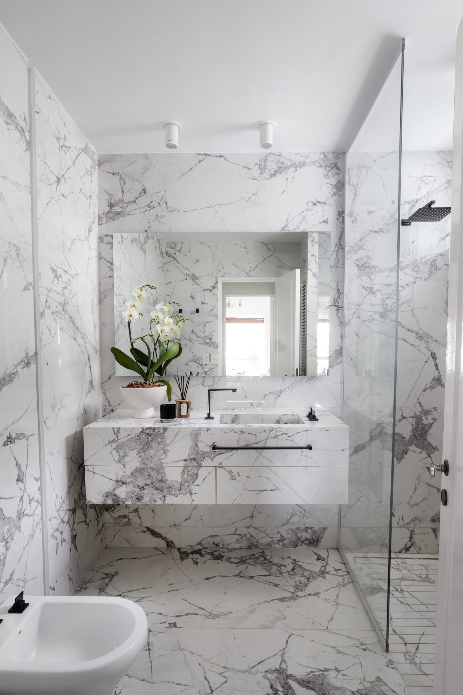 Baño moderno revestido en mármol, con bacha integrada y grifería negra — proyecto Alvear | Redefining luxury, por Ren Studio, en Recoleta