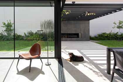 Patio moderno con sillones negros y perro bajo pérgola — proyecto CASA SD28, por GMARQ, en Buenos Aires