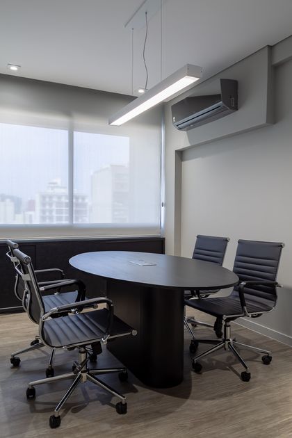 Sala de reuniones moderna con mesa ovalada y sillas de cuero — proyecto Escritório BSA, por Camila Bigolin Arquitetura e Interiores, en Curitiba
