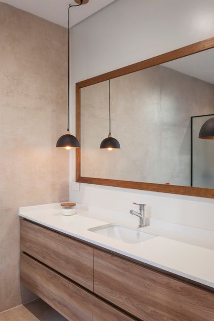Baño moderno con muebles de madera, espejo grande y luces colgantes — proyecto CASA HS143, por A'PRIMA - Arquitectura Sustentable, en km 7.5 Ruta 25