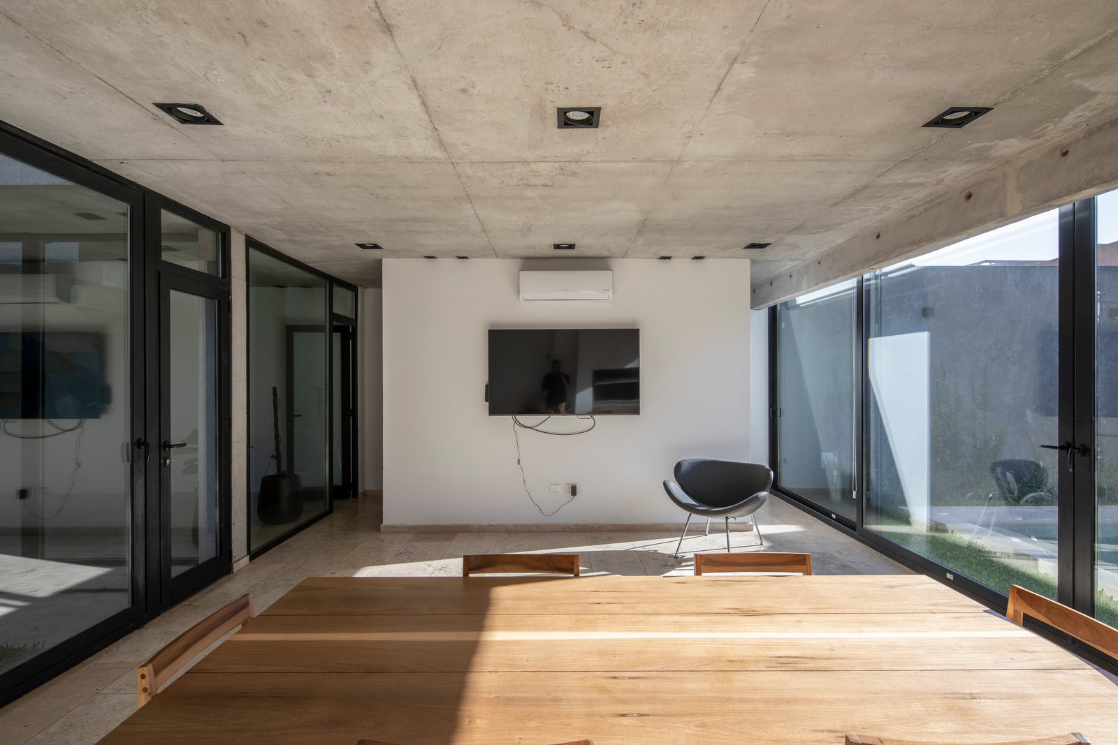 Living comedor moderno con hormigón expuesto y ventanales amplios — proyecto Casa MECHA, por Grupo CRBN, en B1712 Castelar