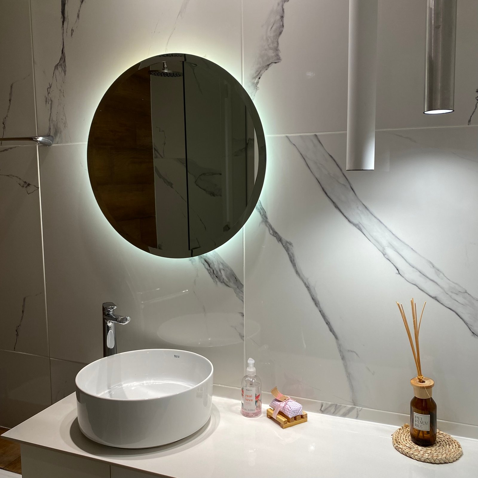 Baño moderno con espejo redondo retroiluminado y paredes de mármol — proyecto Nicolas Repetto, por MDBK Arquitectura, en Caballito