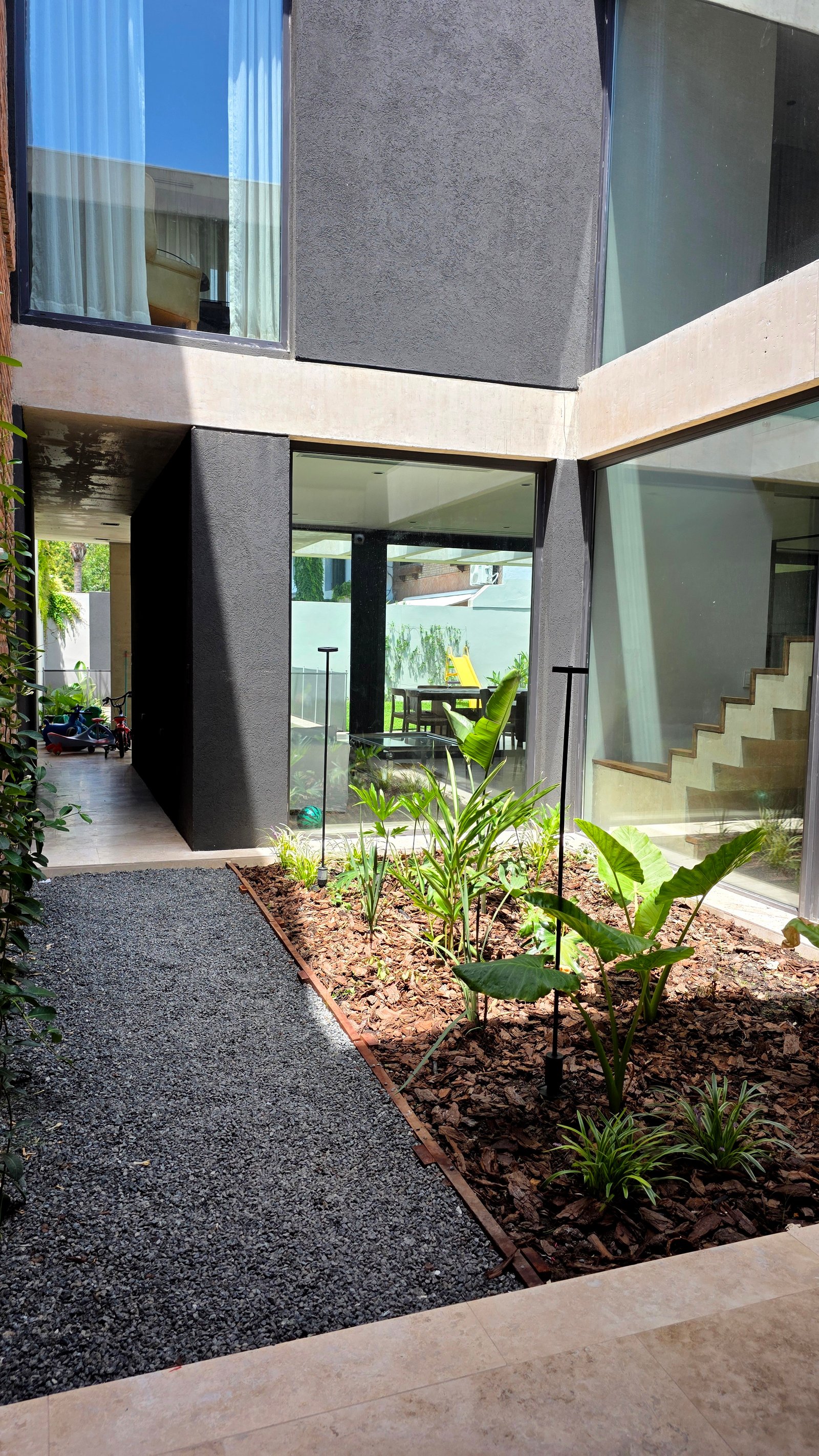 Pátio moderno com jardim interno e fachada envidraçada — projeto Martinez, por Marcela García Brünner Paisajista, em Martínez