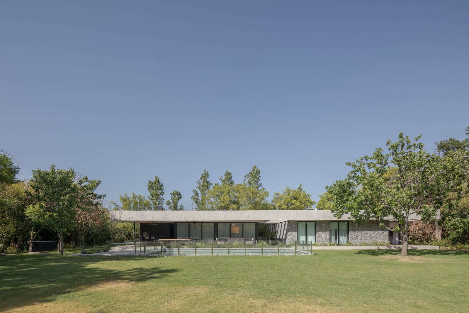 fachada moderna con piscina y pérgola en entorno rural — proyecto Casa PLANALTO, por Grupo CRBN, en Av. Pres. Perón 10298