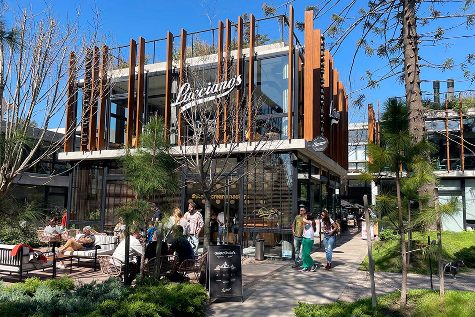 fachada de restaurante moderno com mesas e cadeiras ao ar livre — projeto Thays Parque Leloir, por MUCHTEK, em Parque Leloir