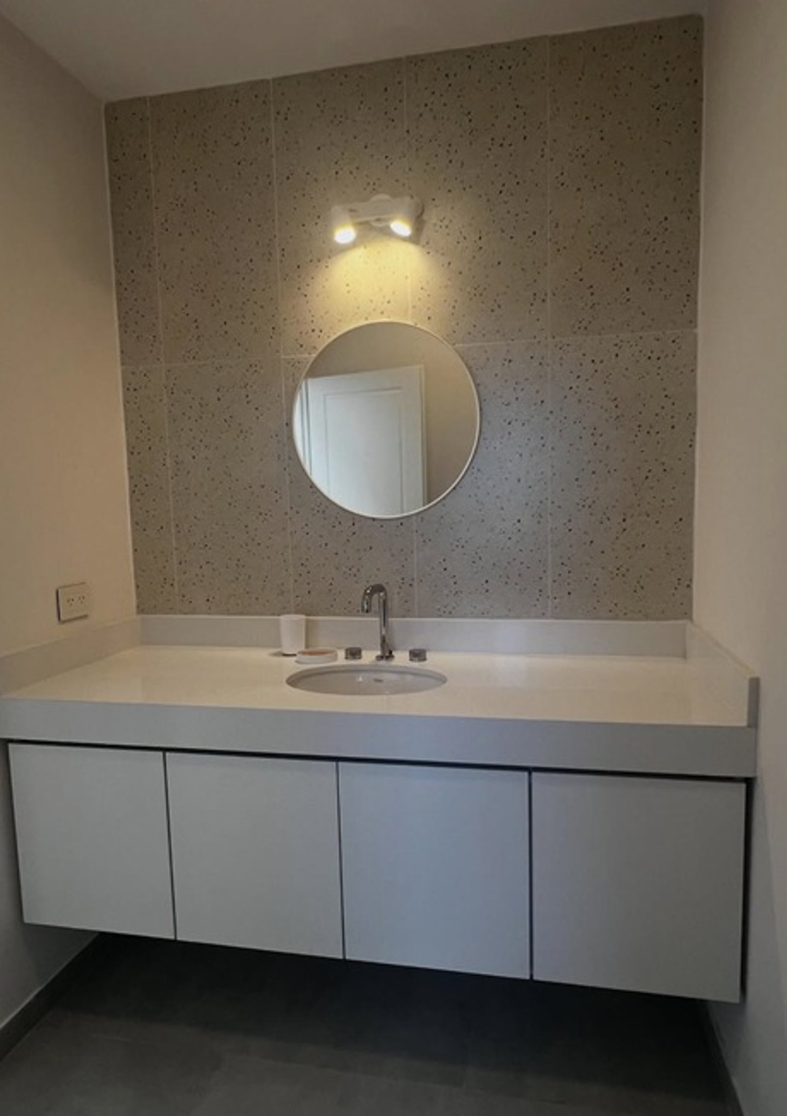 baño moderno con vanitory flotante, espejo redondo y revestimiento de terrazzo — proyecto CARDOS , por Estudio NET Arquitectura , en Manuel Luis de Oliden