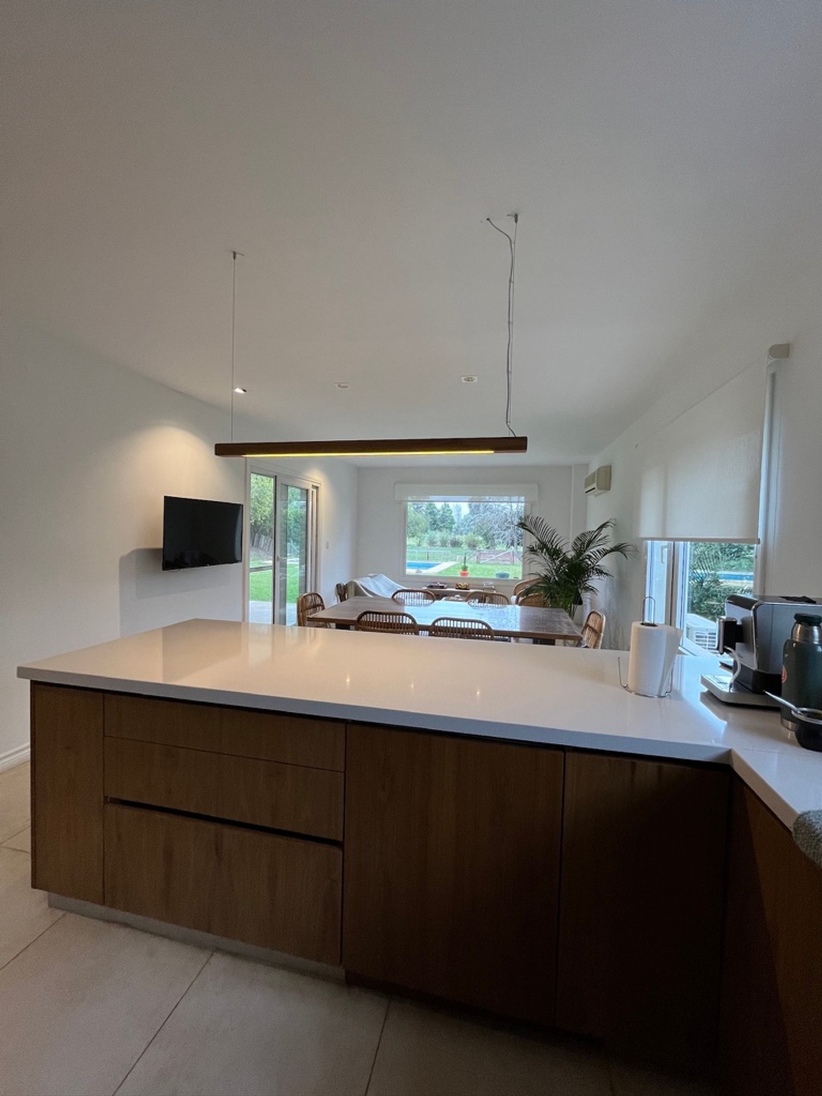 Cozinha moderna com ilha, iluminação linear e sala de jantar integrada — projeto Reforma integral Vivienda., por Arcucci Arquitectura, em Campo Grande