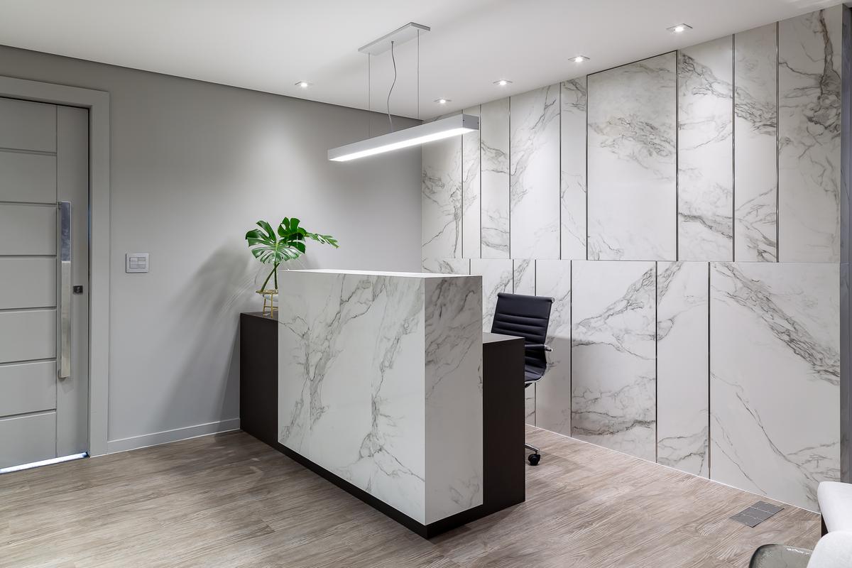 Recepção moderna com painéis de mármore e iluminação linear — projeto Escritório BSA, por Camila Bigolin Arquitetura e Interiores, em Curitiba