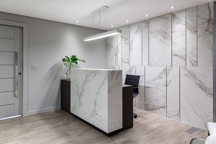 Recepción moderna con revestimiento de mármol y luz lineal — proyecto Escritório BSA, por Camila Bigolin Arquitetura e Interiores, en Curitiba