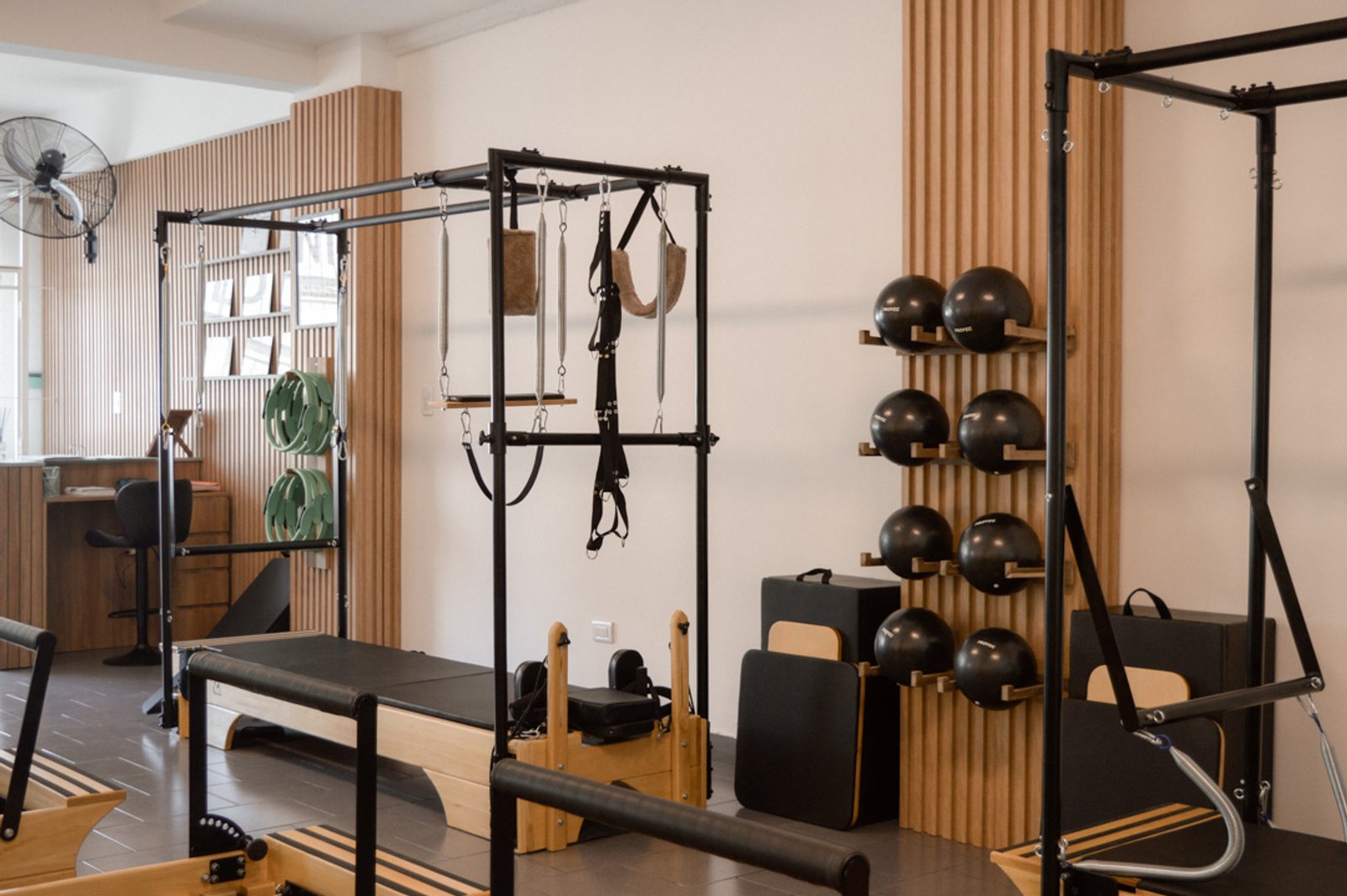 Estudio de pilates moderno con equipos negros y paredes de madera — proyecto Estudio Integral SC - Tandil, por Estudio Agustina Satostegui, en Tandil