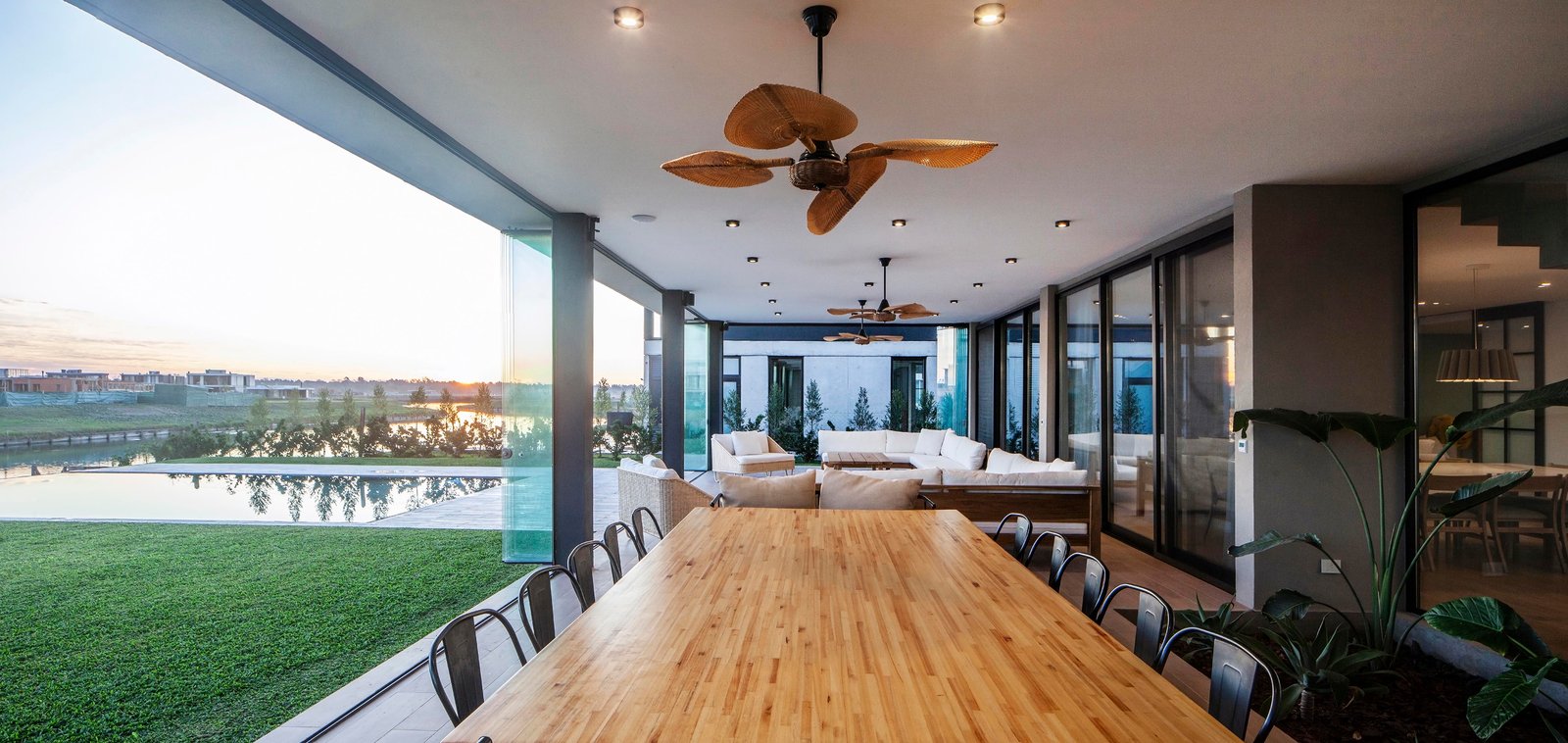 Comedor y living exterior con vista al lago y deck de madera — proyecto CASA C313, por A'PRIMA - Arquitectura Sustentable, en Provincia de Buenos Aires