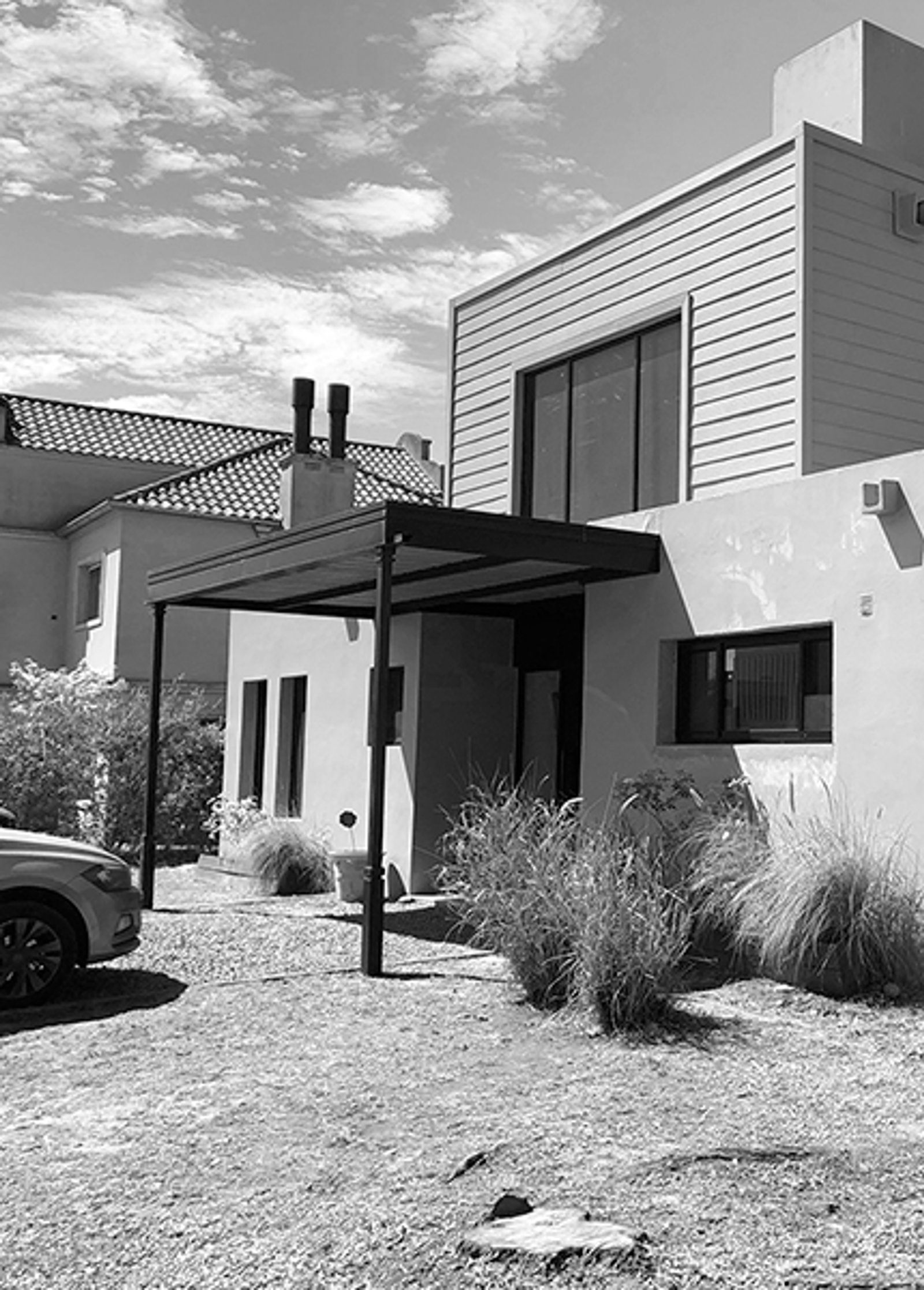 Fachada moderna con pérgola negra y césped ornamental — proyecto Casa coco, por Estudio PK, en B1648 Tigre