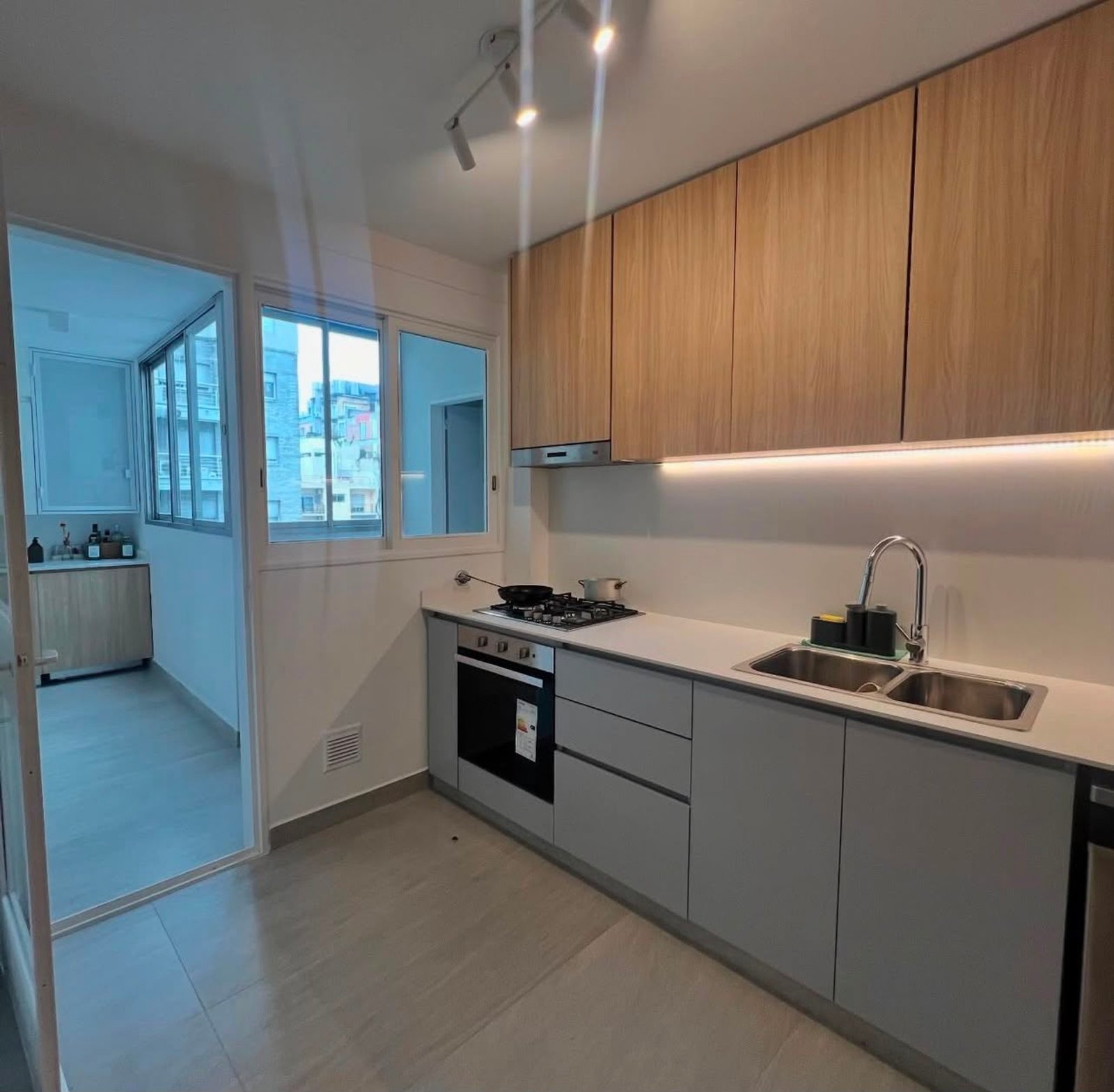 Cozinha moderna em corredor com armários de madeira e bancadas brancas — projeto Zapiola, por Estudio NET Arquitectura, em Zapiola 2645