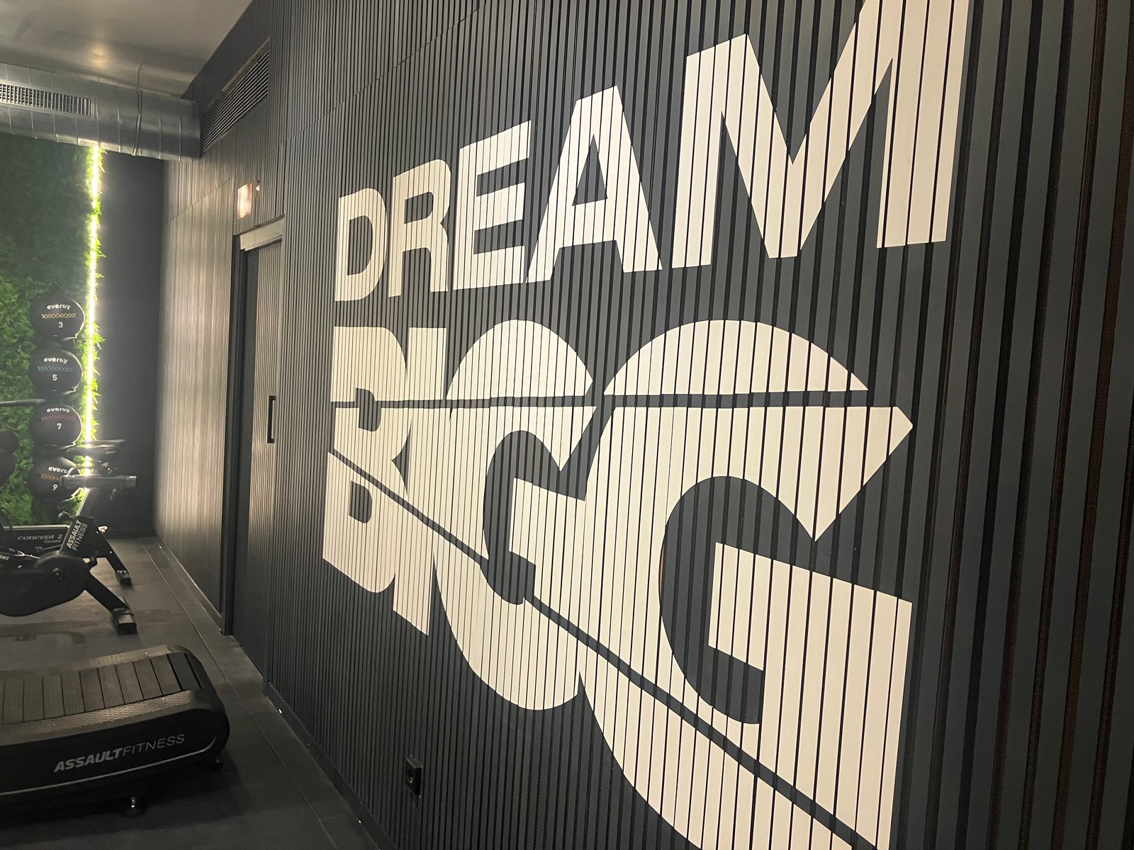 Gimnasio moderno con pared de listones y mensaje inspirador — proyecto BIGG EIXAMPLE, por GeN Arquitectura, en Carrer del Consell de Cent