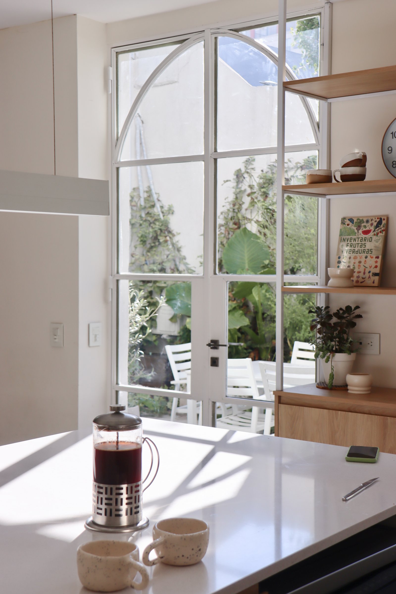 Cocina moderna con ventana arqueada y vista a jardín interior — proyecto Foullier, por Bouré Studio, en Villa Urquiza