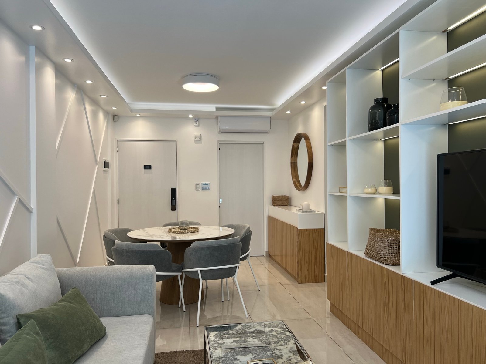 Comedor y living modernos con pared revestida y estanterías integradas — proyecto Basualdo II, por MDBK Arquitectura, en Liniers