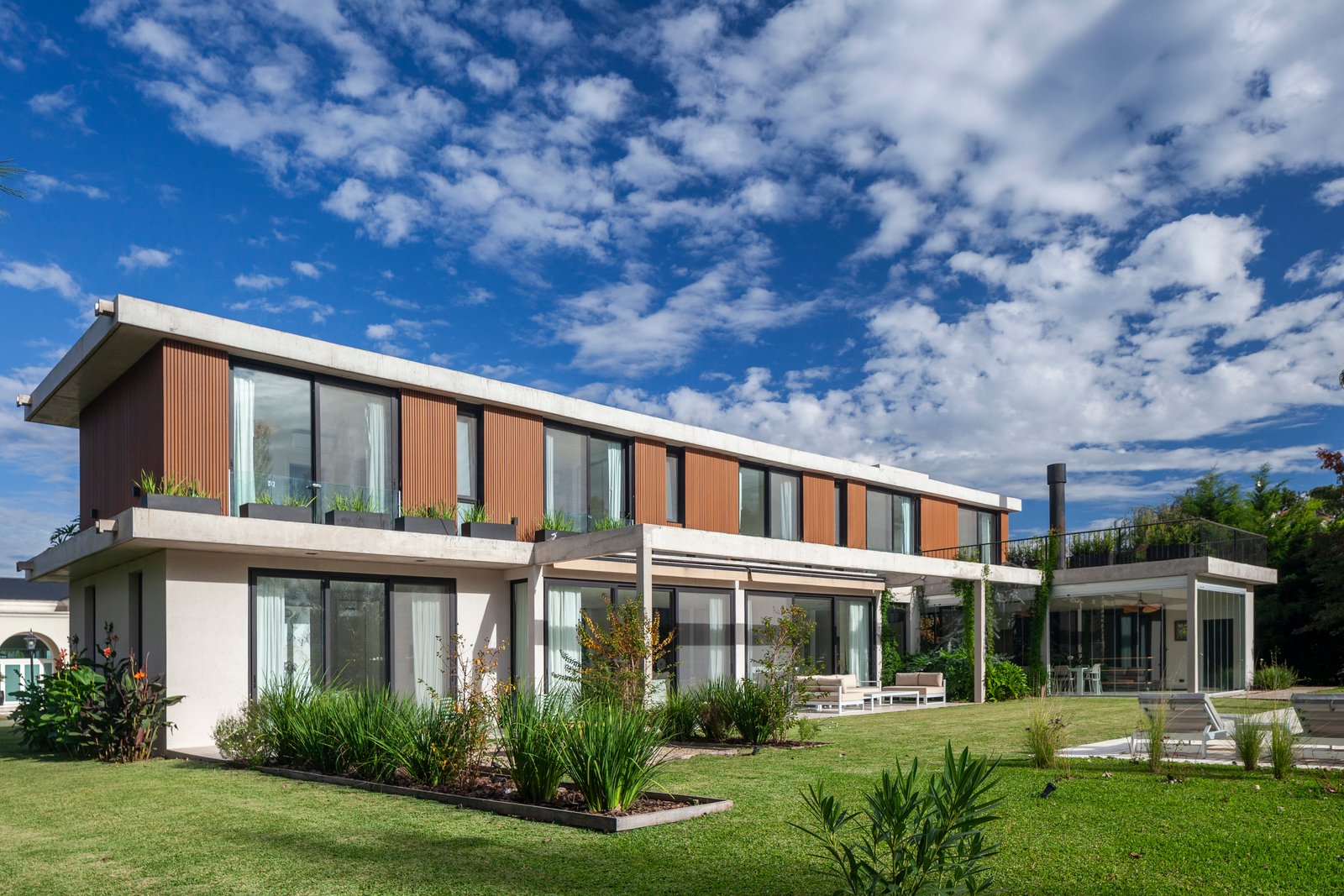 Fachada moderna de casa com amplas janelas e jardim — projeto CASA HS143, por A'PRIMA - Arquitectura Sustentable, em km 7.5 Ruta 25