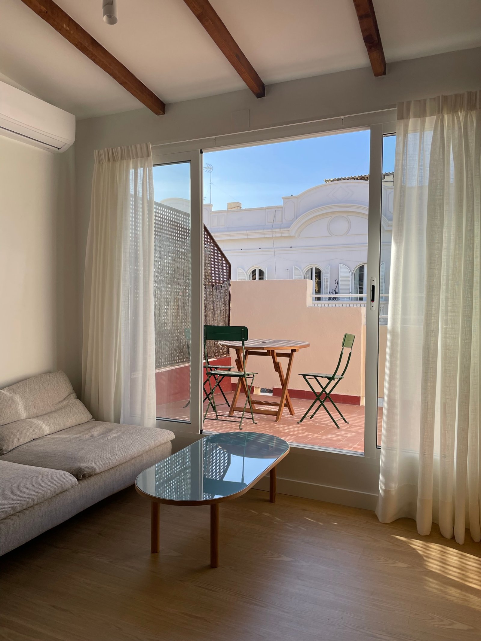 Living con terraza y vigas de madera expuestas — proyecto Burriana, por JT ARQUITECTURA, en Valencia