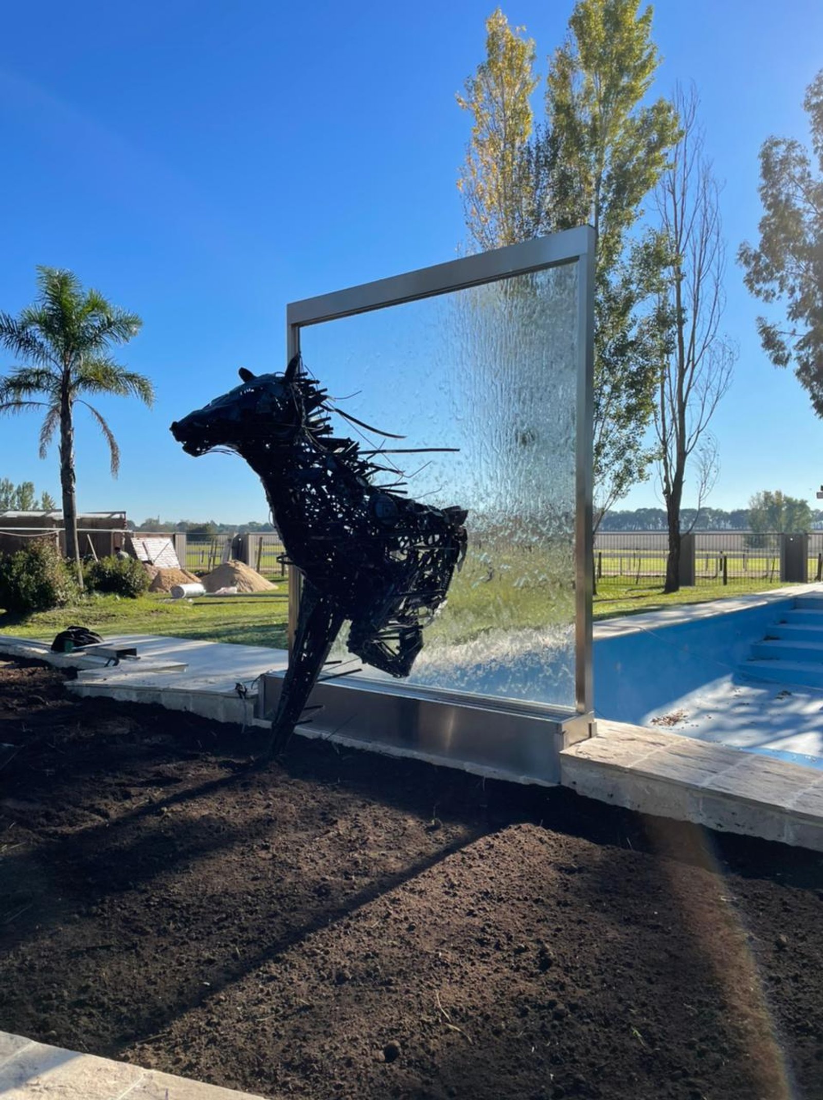 Escultura de cavalo em piscina com cascata de vidro — projeto Fuente de Agua con figura Caballo, por FUENTES Y MUROS .COM.AR, em Canning