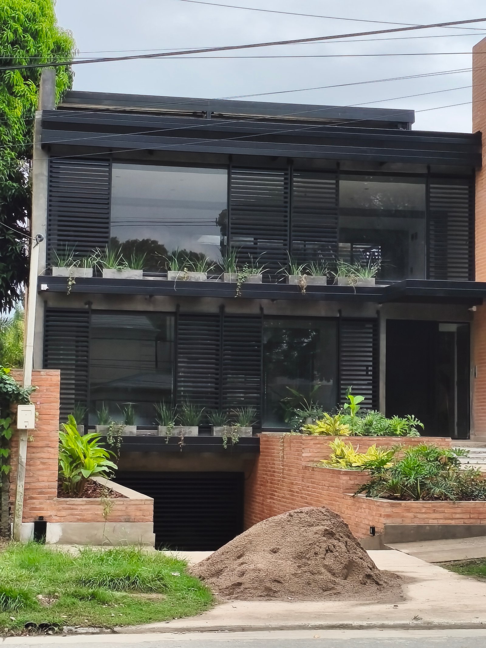 Fachada moderna con plantas en macetas de ladrillo y ventanas grandes — proyecto GARDEN OFFICE, por HMCONSTRUCCIONES, en San Lorenzo 146