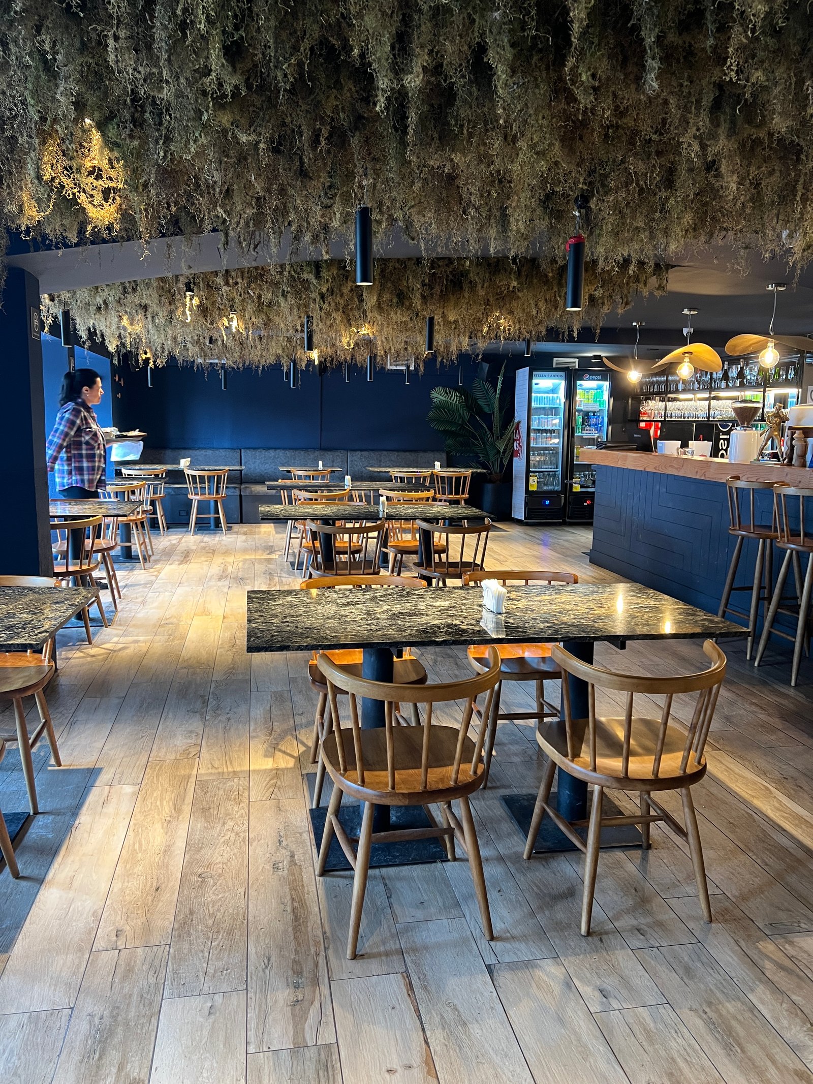 Interior de restaurante com teto de plantas secas e mesas de mármore — projeto Refugio Knapp, por Estudio Losa, em Cerro Leon